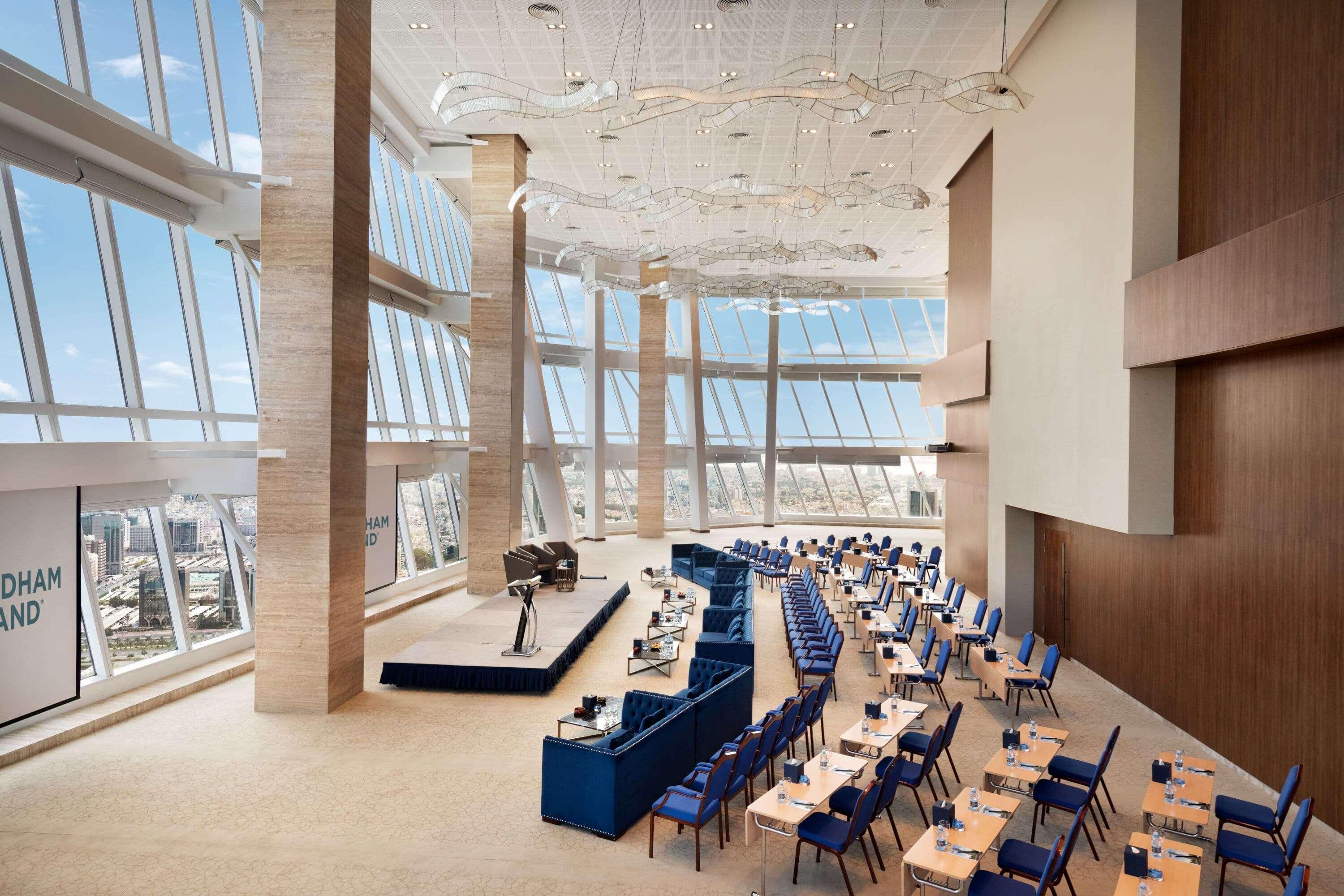 Wyndham Grand Manama Hotel Exterior photo The photo shows a modern conference room or auditorium with large floor-to-ceiling windows that provide ample natural light and a stunning view. The interior is designed with a sleek, contemporary aesthetic, featuring light-colored walls and wooden a